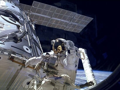 4 dicembre 1998, l'astronauta James Newman saluta durante una passeggiata spaziale nella prima missione dello Space Shuttle (STS-88) verso la Stazione Spaziale Internazionale. STS-88 ha trasportato il modulo americano, Unity che si unirà al modulo russo Zarya, lanciato in orbita il 20 novembre 1998 e qui visibile con il suo pannello solare