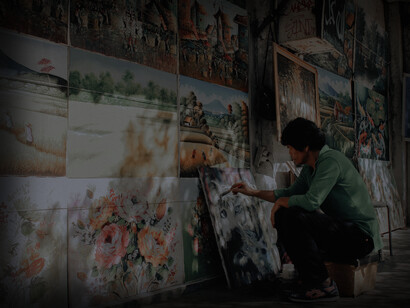 A man sits at a wall painting expressing his creativity 