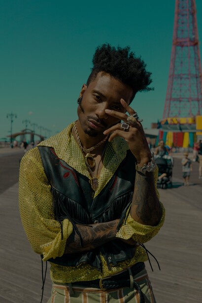 Jovem veste camisa de lantejoulas verdes e colete de couro