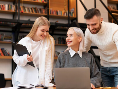 Colleagues engaged in discussion and research in a library, utilizing laptops to explore topics like innovation, the knowledge economy, digital transformation, and technological advancements