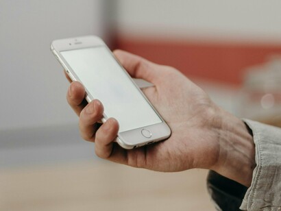 Un homme tenant son smartphone, sur le point de commencer à envoyer des SMS ou à faire défiler les réseaux sociaux