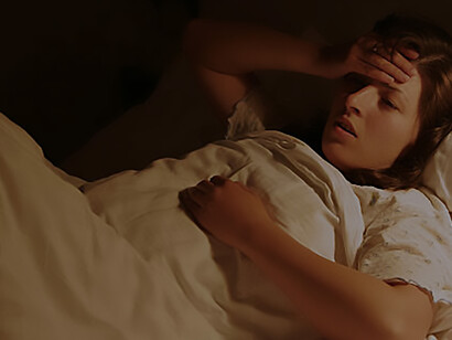 A woman, startled by a recent nightmare, lies in bed, overcome with fear