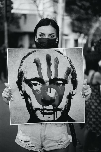 Woman holding sign with Putin's face and bloody hand