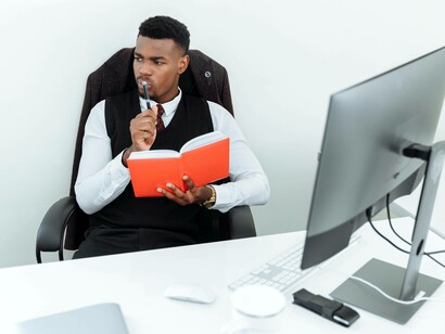 An economics student pondering his notes from his computer