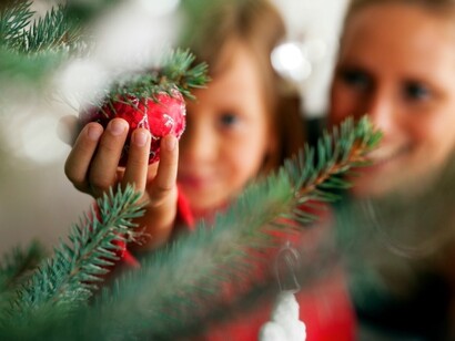Una niña ayuda a su madre a decorar el árbol de Navidad
