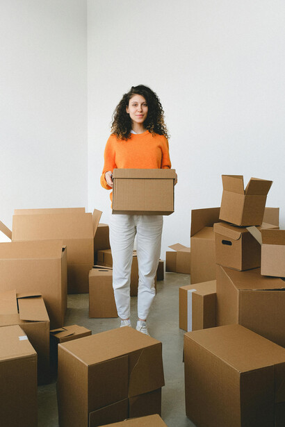 A young woman settles into a new space, surrounded by cardboard boxes during relocation