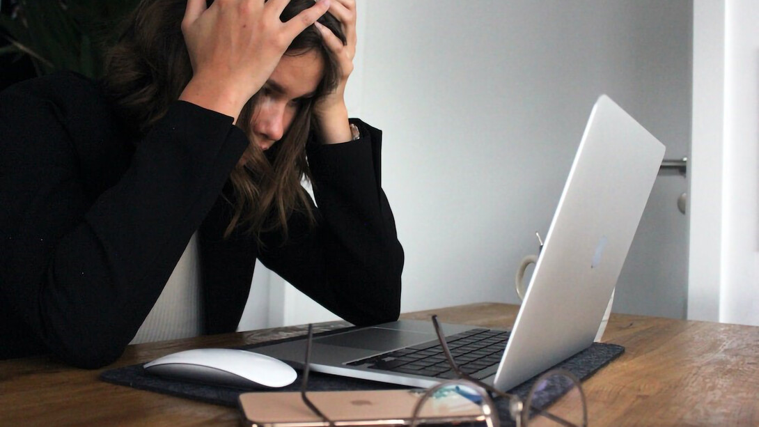 a business woman who is stressed and frustrated in black long sleeve shirt covering her face with her hands
