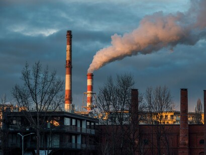 Industrial smokestacks releasing thick emissions into the atmosphere, representing humanity's growing contribution to climate change