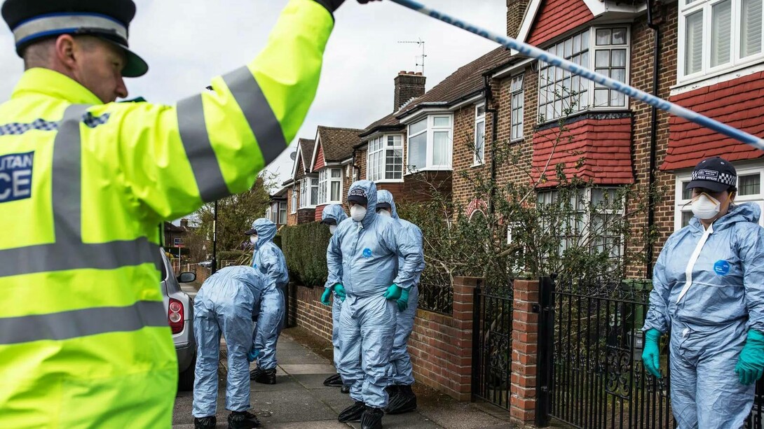 A policer officer holding up the police tape for the crime scene investigators