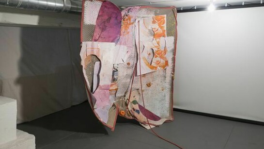 Eric Mack, Pain After Heat, 2013, rope, paper, acrylic paint, dye, ink, dried orange peel, wood, plastic, magazine image and gromets on a quilted moving blanket, 77 x 90 x 49 inches