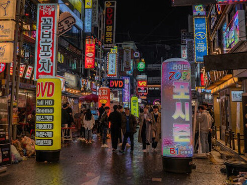 Under the glow of streetlights in Seoul, South Korea, fashionable residents stroll through the lively streets, embodying the city’s effortless blend of cutting-edge style and cultural heritage