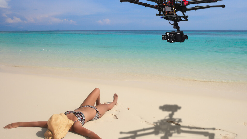 Un dron sobrevolando a una chica que toma el sol en la playa
