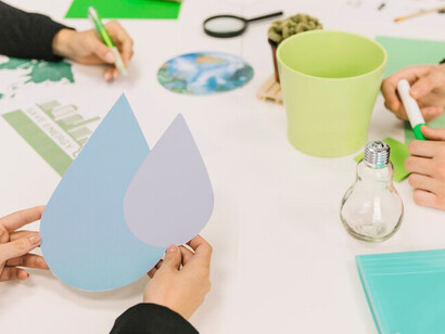A businessperson's hand holding a water drop symbol, illustrating themes of sustainability and environmental awareness
