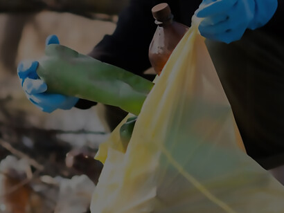 A man diligently collects scattered plastic bottles from the ground, actively contributing to recycling efforts and combatting pollution
