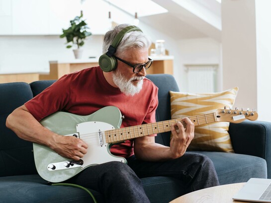 Senior man enjoying music while playing an electric guitar