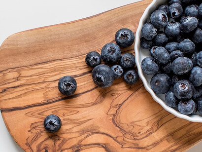 Blackberries resting on a rich brown wooden chopping board