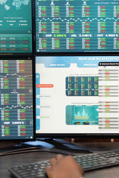 Dati e grafici su molteplici schermi, che illustrano l'andamento del mercato azionario