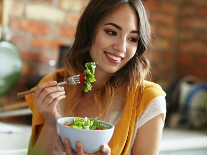After the holidays, a young woman refreshes her diet with a nutritious salad filled with fresh fruits and vegetables