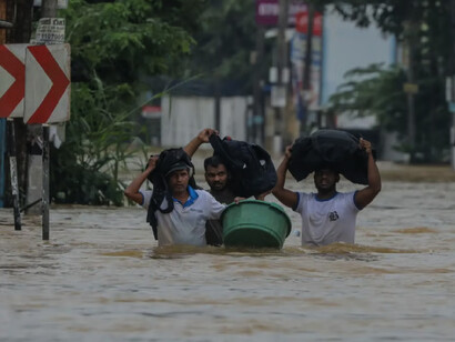 Sri Lankan flood victims wade through a flooded road during heavy rainfall in a suburb of Colombo
