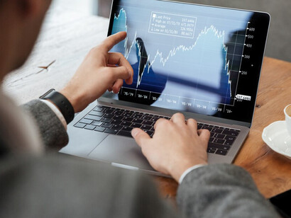 A businessman sitting at a café table, analyzing the stock market on his laptop