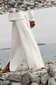 Barefoot on the rocks, a model steps into herself grounded in reflection and free to feel
