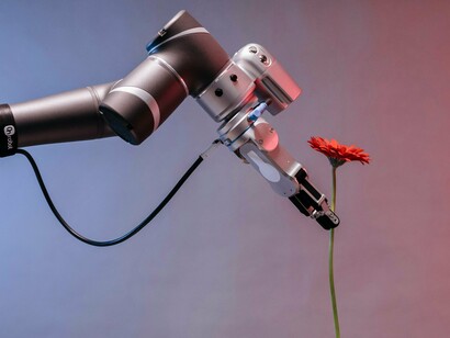 Robô oferece uma flor. O mercado precisa equilibrar essa febre especulativa com a apreciação da arte como uma experiência cultural. Como já ocorre em outras frentes, é fundamental questionar se as vendas de arte por IA são um reflexo de seu valor artístico ou apenas um resultado de tendências mercadológicas e tecnológicas