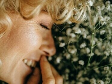 Mulher feliz com flores. Entender a felicidade como entorpecimento da mente, ou seja, afastando-a dos problemas e desejos que ela tem, é uma outra estratégia que pode ser confundida com felicidade. Nesta situação, jogos, bebidas e até mesmo passar horas assistindo séries e filmes (comédias, geralmente) apenas vão distrair a mente. Ela ingenuamente achará, por algum tempo, que está muito bem, enquanto está apenas se entretendo