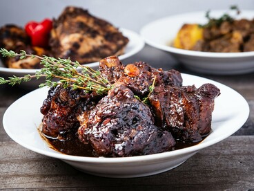 Tender oxtail plated with fresh herbs and glossy reduction, reflecting the changing social value assigned to overlooked cuts