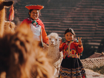 Una donna e una ragazza con abiti tradizionali e un alpaca in Pisac, Perù