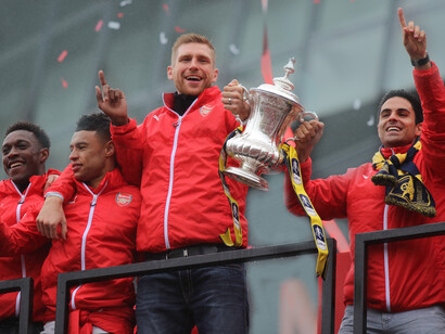 Per Mertesacker et Mikel Arteta soulèvent la FA Cup lors de la parade du trophée