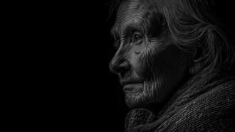 Em preto e branco, o perfil de uma mulher idosa revela um rosto marcado pelas rugas e uma expressão pensativa. A luz e as sombras realçam os traços de uma vida atravessada pelo tempo, conferindo ao retrato uma intensidade silenciosa. O envelhecimento transforma o corpo, mas não apaga a história, a identidade ou a dignidade de quem envelhece. Talvez seja justamente nesse rosto que encontramos um lembrete de que a força não precisa permanecer visível para continuar fazendo parte de quem somos
