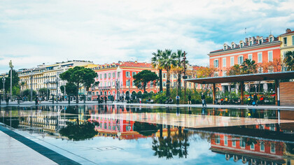 The allure of Nice, France, as people stroll along the streets near elegant buildings, immersing themselves in the picturesque ambiance of this enchanting destination on the French Riviera