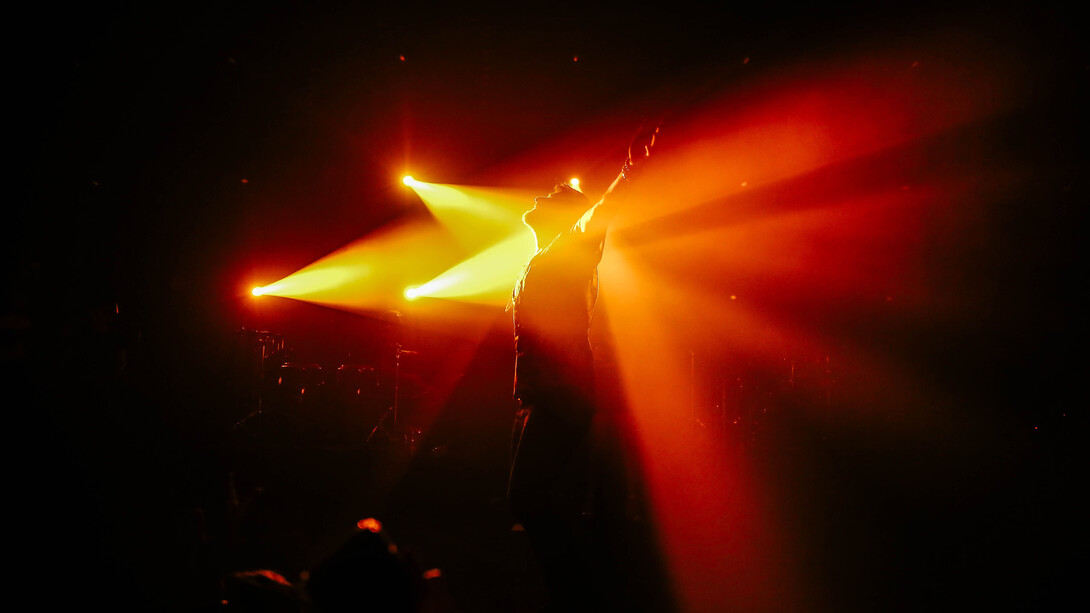 Ator em perfomance teatral sob jogo de luz no palco 