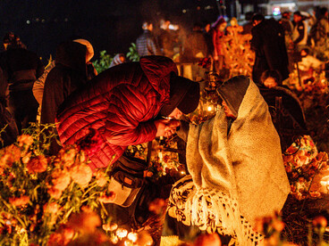Families gather in a cemetery illuminated by candles during Mexico’s Day of the Dead, paying tribute to departed loved ones