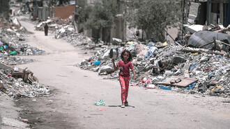 Una niña camina por las calles de la destruida Gaza en busca de comida