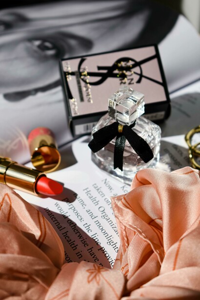 A bottle of perfume and a lipstick are placed on a magazine page