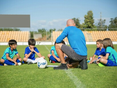 A coach sharing a moment with his team, symbolising how sport can nurture confidence rather than ranking ability