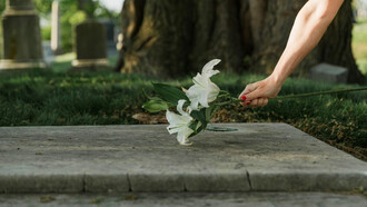 Un mujer deja unas flores encima de la tumba de un ser querido