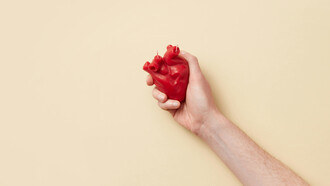A red heart held tightly on one hand