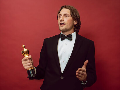 In a tailored suit, a triumphant man holds a prestigious award, his joy apparent as he emanates strength, enthusiasm, and ambition, encapsulating the essence of resounding success