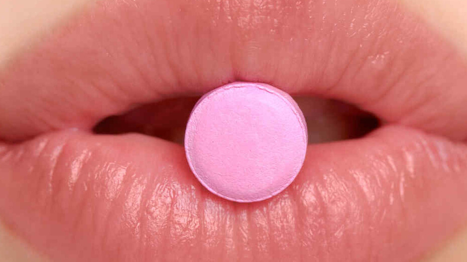 Una mujer se dispone a tragar una pastilla