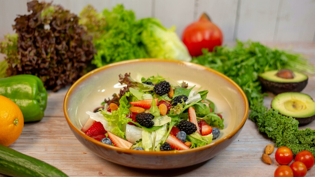 A vibrant vegetable salad presented in an earthy brown ceramic bowl