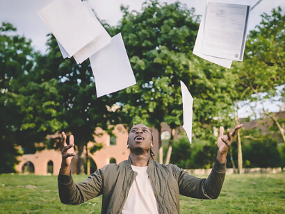 A jubilant man enthusiastically tosses papers into the air, embodying the spirit of success, motivation, ambition, and the achievement of his goals