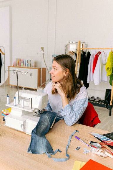 A designer in a fashion studio workspace, sewing and cutting fabric using zero-waste pattern techniques