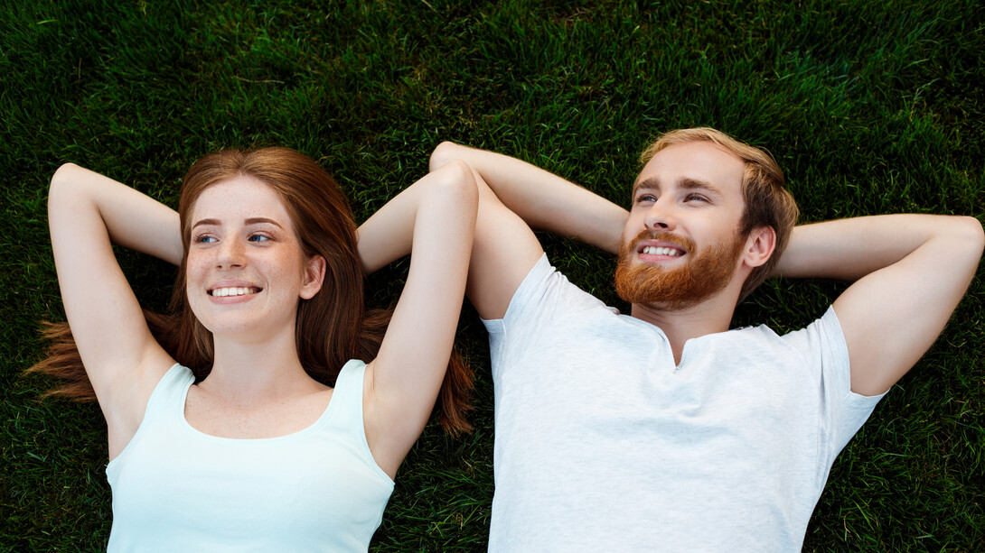 Una coppia felice, un uomo e una donna, giacciono sull'erba sorridendo