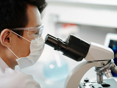 A man looks through a microscope, symbolizing the fusion of bioengineered crops, sustainable food technology, and the future of farming