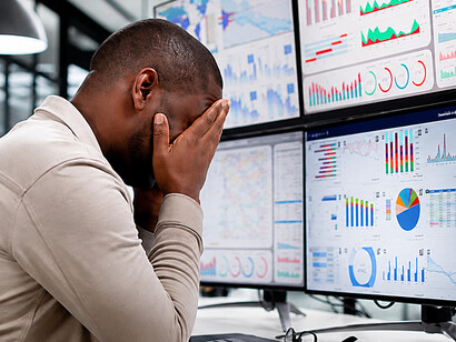 A stressed professional struggles to manage endless streams of data across multiple screens, highlighting the realities of digital overload and mental exhaustion