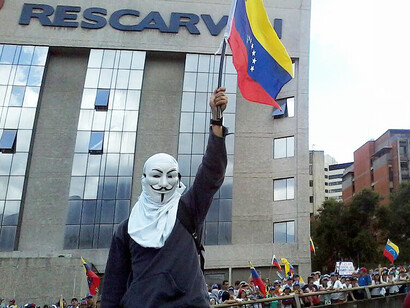Protester wearing an Anonymous mask and waving a Venezuelan flag at a rally in Venezuela