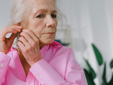 An elderly woman holding a mirror, reflecting on aging