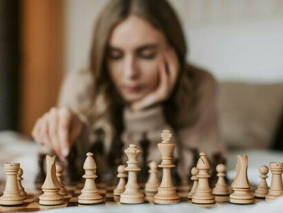 Une femme joue aux échecs allongée sur le lit, dans une configuration confortable